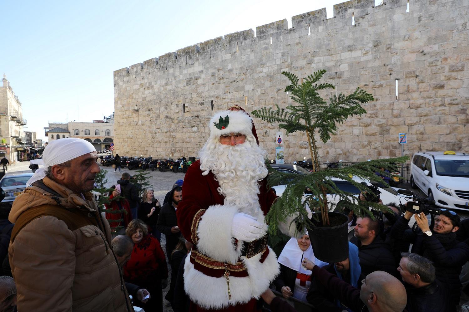 شاب يرتدي ملابس سانتا كلوز بمناسبة قرب عيد الميلاد في القدس المحتلة. (رويترز)