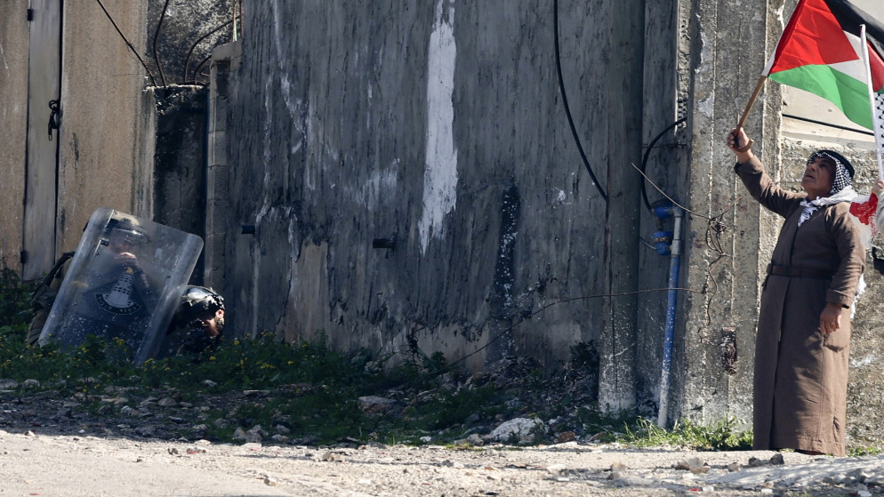 فلسطيني يلوّح بالعلم الوطني خلال مواجهات مع قوات الاحتلال الإسرائيلي في قرية كفر قدوم، 17 شباط/فبراير 2023. (أ ف ب)