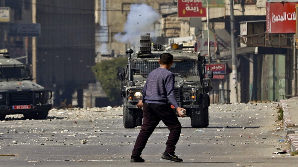 شاب فلسطيني يحمل حجرا في مواجهة قوات الاحتلال الإسرائيلي في نابلس في الضفة الغربية المحتلة. (رويترز)