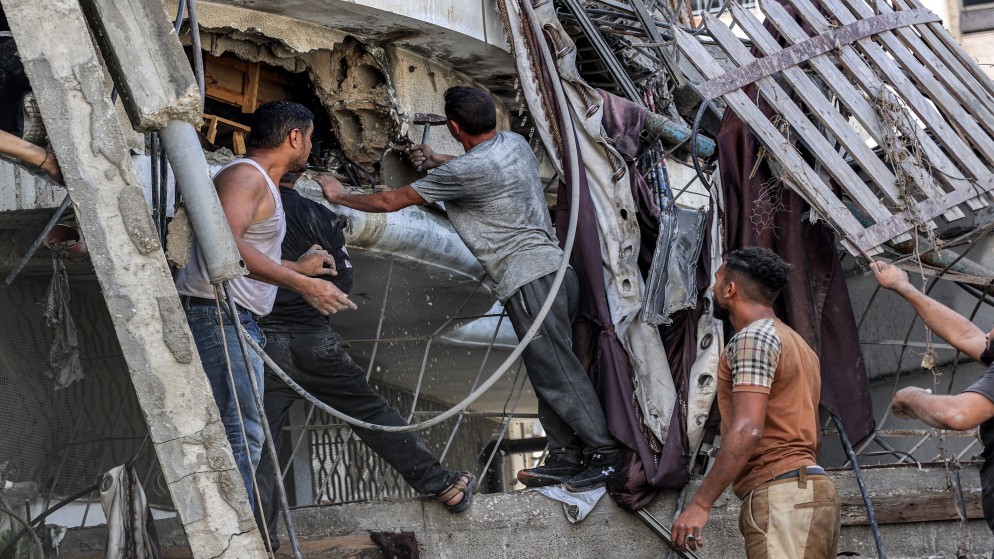 فلسطينون خارج مبنى منهار وهم يحاولون انتشال رجل من تحت الأنقاض بعد قصف إسرائيلي في منطقة الصفطاوي في جباليا شمال قطاع غزة . 15 أكتوبر 2024 (أ ف ب)