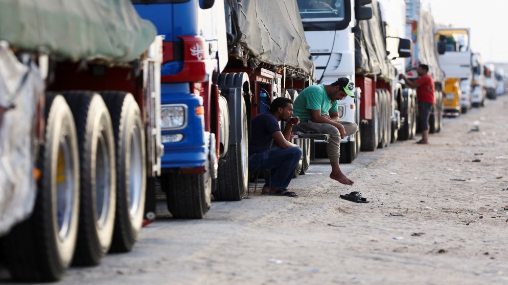 سائقو شاحنات في العريش يجلسون بالقرب من شاحنات المساعدات المتجهة إلى غزة، 4 تموز 2024. (رويترز)