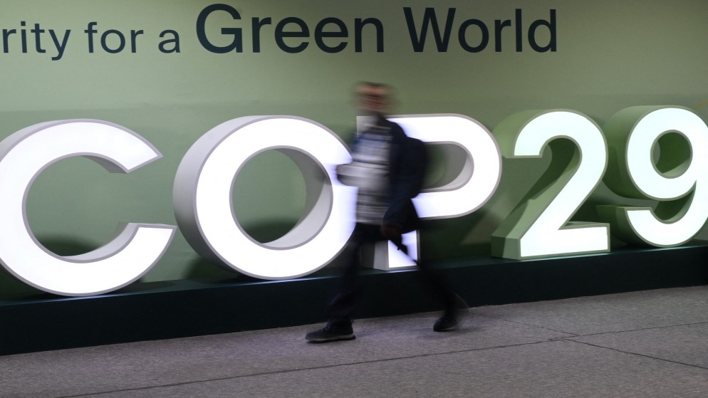 مشاركون يمرون أمام شعار مؤتمر الأمم المتحدة لتغير المناخ (COP29) خلال مؤتمر الأمم المتحدة لتغير المناخ (COP29) في باكو، أذربيجان، في 21 نوفمبر 2024(AFP)