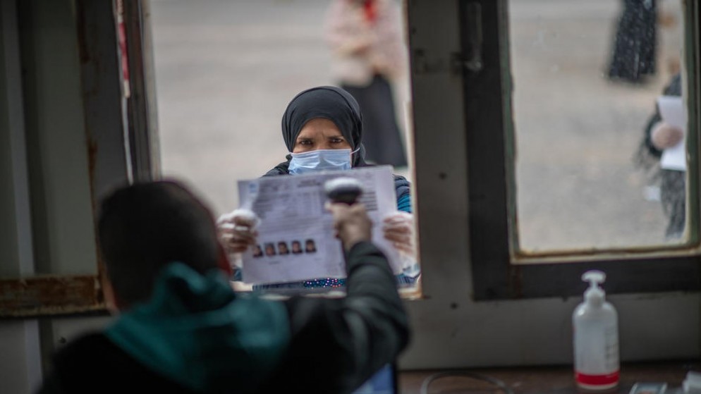 صورة أرشيفية للاجئة سورية تقف للحصول على مساعدتها النقدية الشتوية في مخيم الأزرق. (UNHCR)