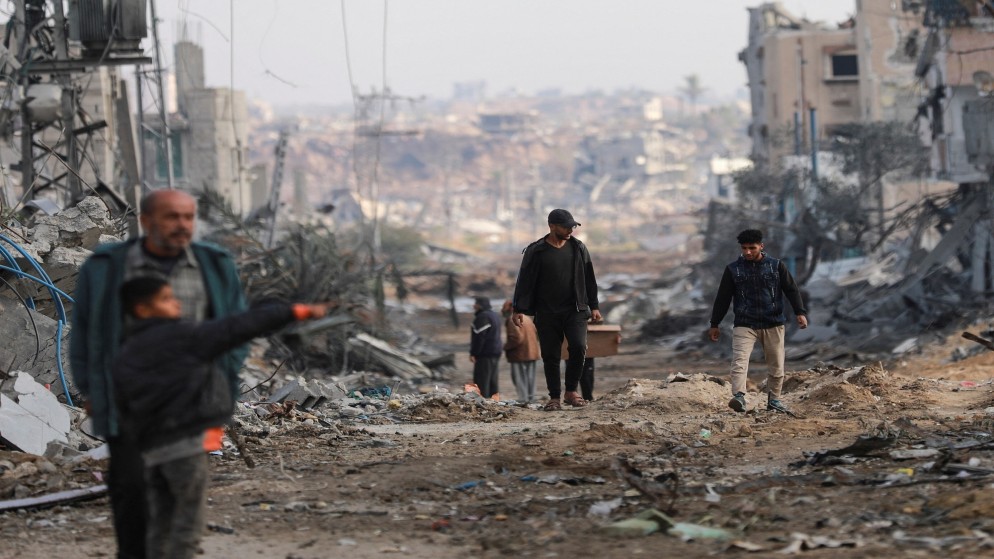 فلسطينيون يسيرون بجوار مبان متضررة بعد انسحاب قوات الاحتلال الإسرائيلي من جزء من النصيرات وسط قطاع غزة. 29 تشرين الثاني، 2024. (رويترز)