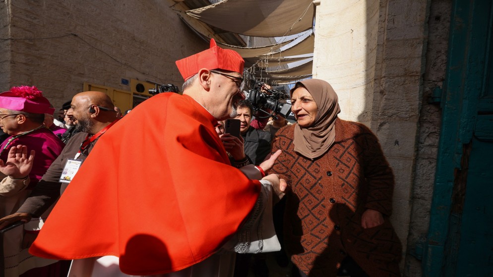 البطريرك اللاتيني في القدس بييرباتيستا بيتسابالا يصافح امرأة في مدينة بيت لحم في الضفة الغربية المحتلة .24 ديسمبر 2024.(أ ف ب)