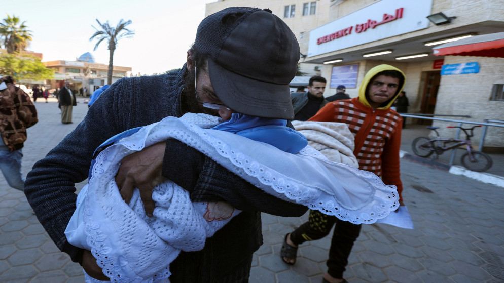 فلسطيني يحتضن طفله الرضيع الذي استشهد جراء البرد وانعدام وسائل التدفئة في دير البلح. قطاع غزة. 29 ديسمبر 2024. (رويترز)