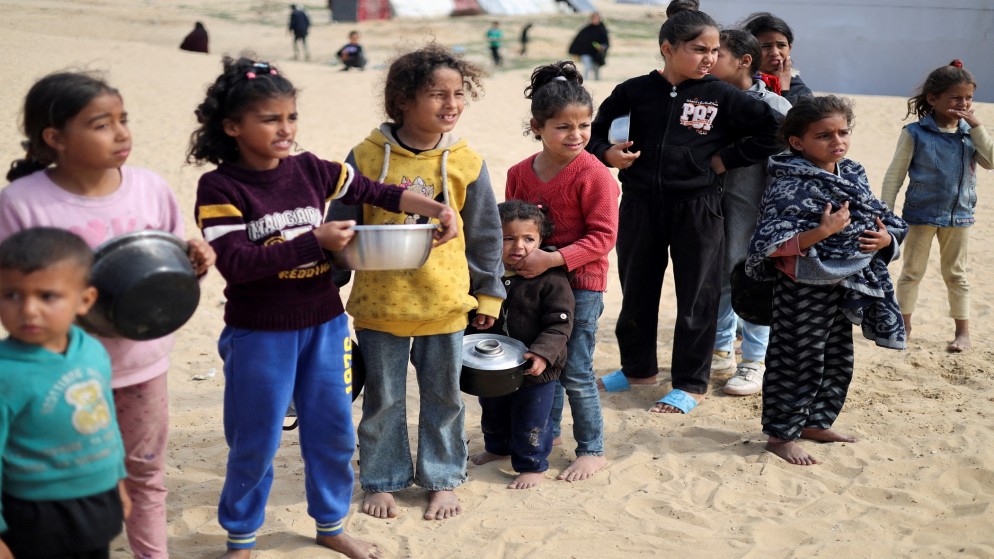 أطفال فلسطينيون ينتظرون طعاما جاهزا في رفح في جنوب قطاع غزة. (رويترز)