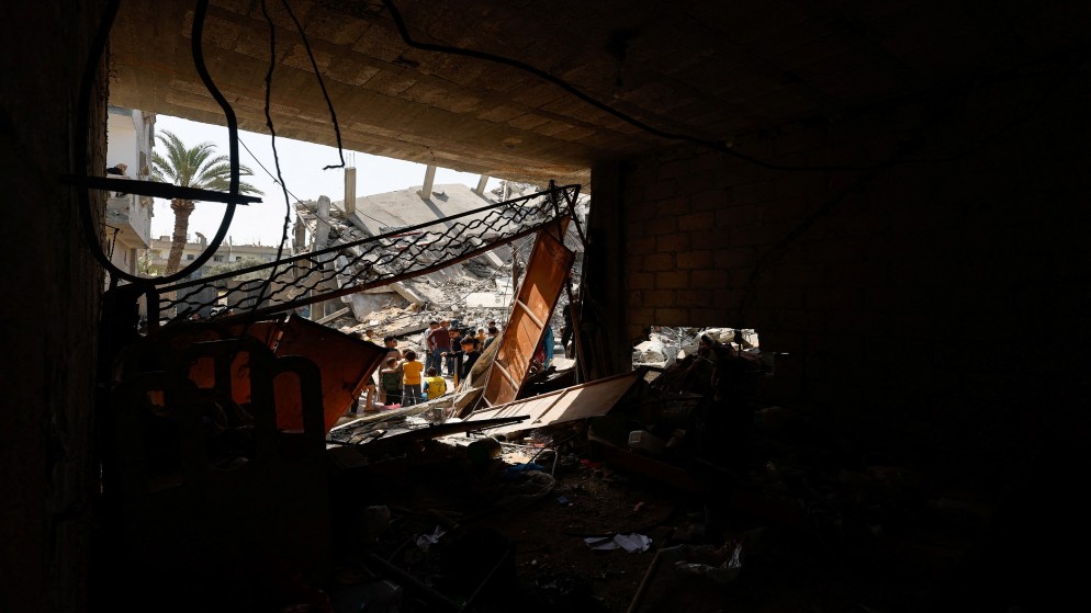 فلسطينيون قرب مبنى مدمر بفعل ضربات إسرائيلية على رفح في جنوب قطاع غزة. (رويترز)
