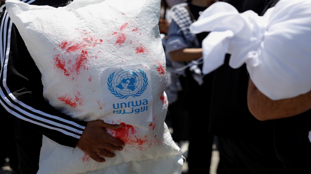 فلسطيني يحمل حقيبة مساعدات عليها شعار وكالة غوث وتشغيل اللاجئين الفلسطينيين (أونروا) وعليها دماء مزيفة. 15 مايو 2024. (رويترز)