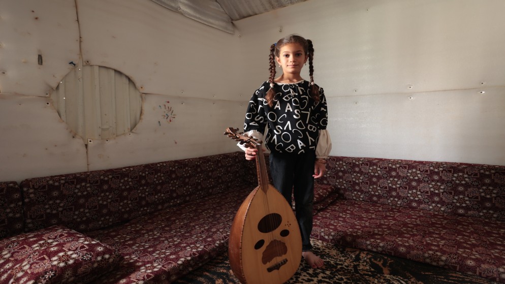 اللاجئة السورية غزل الغزاوي (9 سنوات) التي تنحدر من درعا مع عود والدها في مخيم الأزرق. (صلاح ملكاوي/ المملكة)