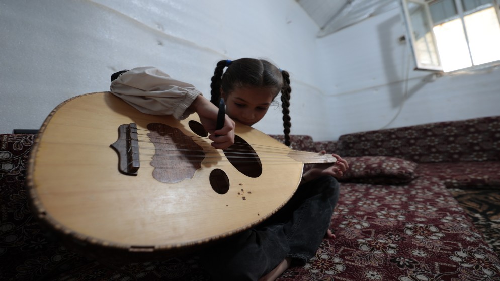 اللاجئة السورية غزل الغزاوي (9 سنوات) التي تنحدر من درعا مع عود والدها في مخيم الأزرق. (صلاح ملكاوي/ المملكة)