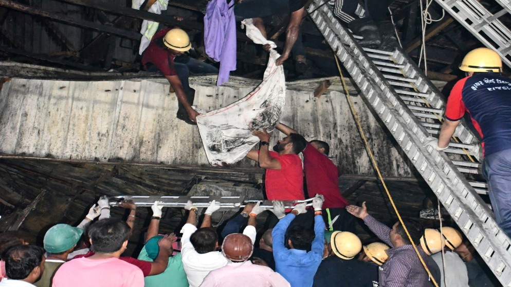 عمال الإنقاذ يزيلون جثة ضحية من منطقة ألعاب محترقة بعد حريق في راجكوت بولاية جوجارات الغربية بالهند، 25 مايو 2024. (رويترز)