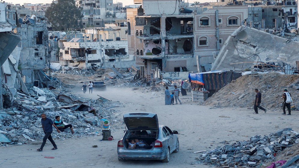 فلسطينيون يسيرون وسط منازل دمرتها غارة إسرائيلية في خان يونس بجنوب قطاع غزة .29 مايو/ أيار 2024.(رويترز)
