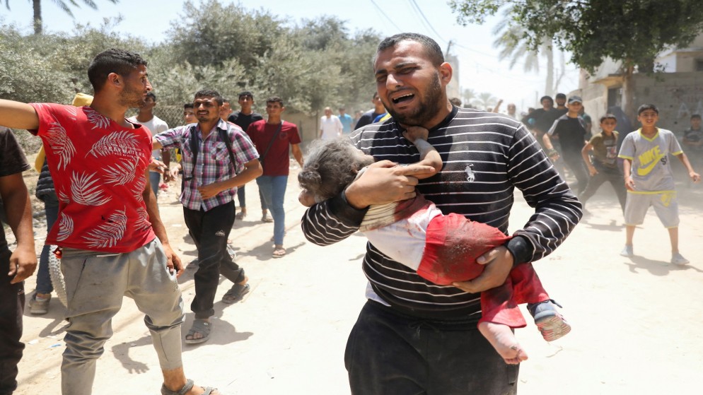 رجل فلسطيني يحمل طفلة أصيبت في أعقاب غارة إسرائيلية في دير البلح بوسط قطاع غزة .14 حزيران /يونيو 2024. (رويترز)
