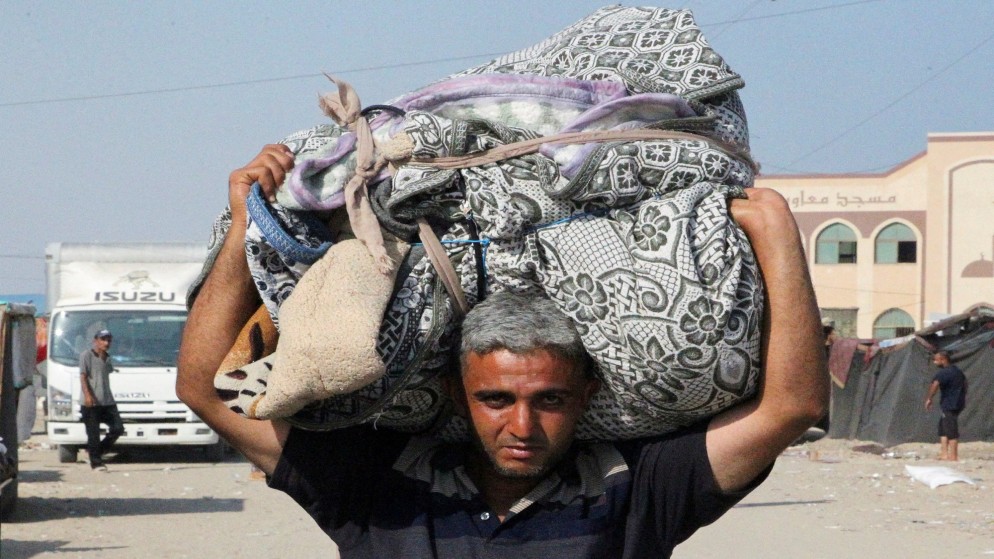 فلسطيني يحمل متعلقاته أثناء فراره من رفح بسبب عملية عسكرية إسرائيلية. جنوب قطاع غزة. 13 يونيو، 2024. (رويترز)