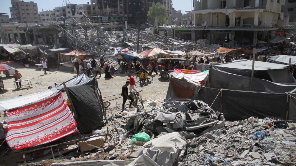 فلسطينيون يسيرون بالقرب من منازل دمرت إثر العدوان الإسرائيلي على مخيم جباليا شمالي قطاع غزة. 19 حزيران/ يونيو، 2024. (رويترز)