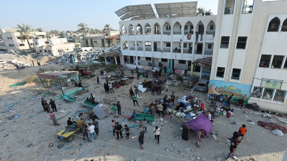 صورة سابقة لفلسطينيين في محيط مدرسة دمرت بعد قصف إسرائيلي على دير البلح وسط قطاع غزة. (رويترز)