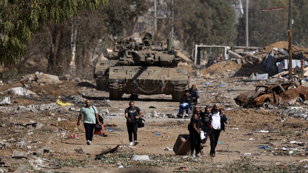 صورة سابقة لنازحين فلسطينيين خلال عبورهم أمام دبابات إسرائيلية في قطاع غزة. (أ ف ب)