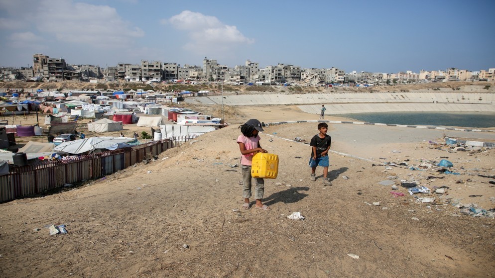 طفلان فلسطينيان قرب تجمع لمياه الصرف الصحي بجانب مخيم للنازحين في خان يونس في جنوب قطاع غزة. (رويترز)