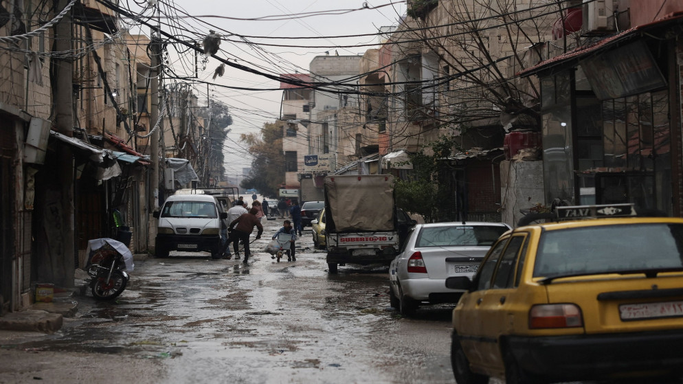 صبي يحمل أغراض لعائلته بمساعدة دراجة في الطقس البارد بعد هطول أمطار غزيرة في معضمية الشام في ريف دمشق. 29/12/2024. (رويترز)