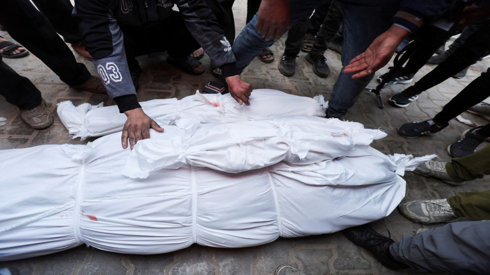 فلسطيني بجوار جثامين شهداء فلسطينيين في مستشفى شهداء الأقصى، في دير البلح في وسط قطاع غزة، 14 يناير 2025. رويترز