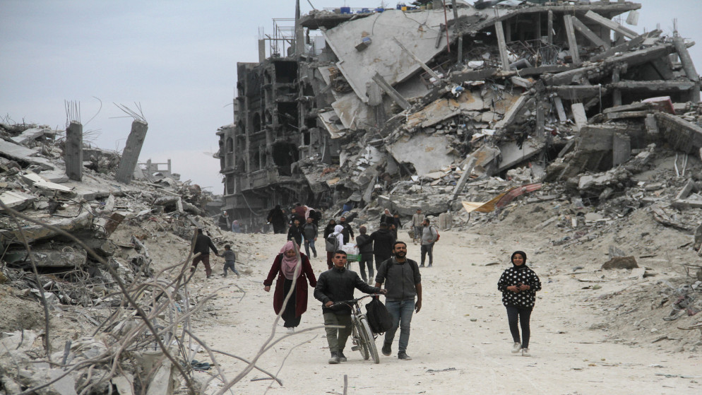 فلسطينيون يسيرون بين أنقاض المباني والمنازل التي دمرت خلال الحرب، في جباليا في شمال قطاع غزة، 22 يناير 2025. (رويترز)