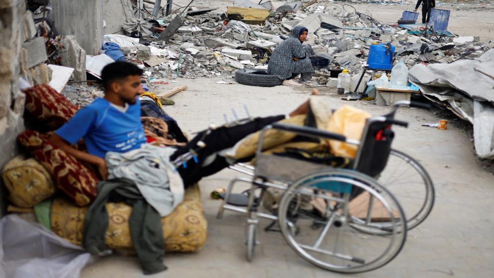 فلسطينيون يجلسون بالقرب من أنقاض مبانٍ دمرت خلال العدوان الإسرائيلي على رفح جنوبي قطاع غزة. 22 كانون الثاني/ يناير 2025. (رويترز)