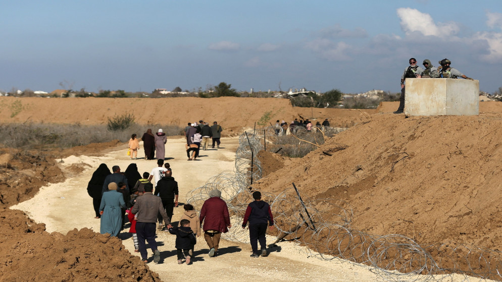 أفراد أمن أجانب يراقبون الفلسطينيين النازحين أثناء عودتهم من الجنوب إلى منازلهم في شمال غزة، بالقرب من مدينة غزة، 27 يناير 2025. (رويترز/حاتم خالد)