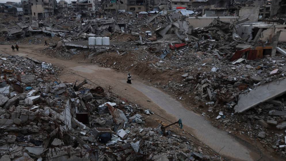 فلسطينيون يسيرون بين أنقاض مبان دمرها الاحتلال الإسرائيلي، في خان يونس جنوبي قطاع غزة، 24 شباط 2025. (رويترز)