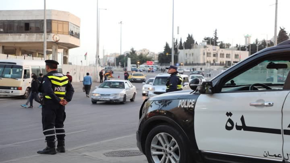 رجلا أمن يقفان أمام دورية نجدة. (مديرية الأمن العام)