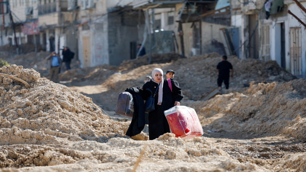 فلسطينيون يسيرون على طريق متضرر أثناء مغادرتهم مخيم نور شمس للاجئين في الضفة الغربية، 26 شباط 2025. (رويترز)